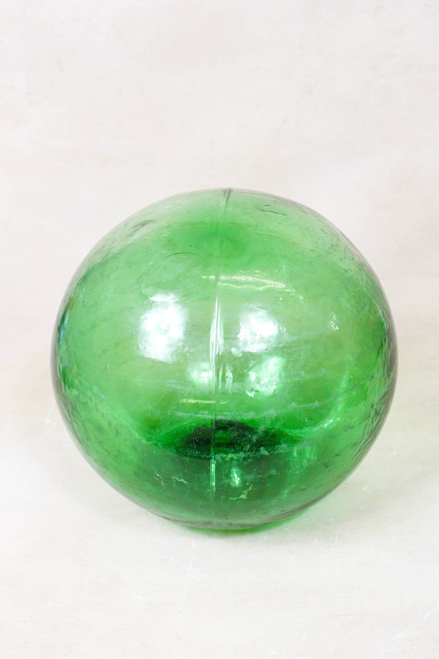 Antique emerald green glass fishing buoy GB3 viewed from another angle showing its hand-blown character