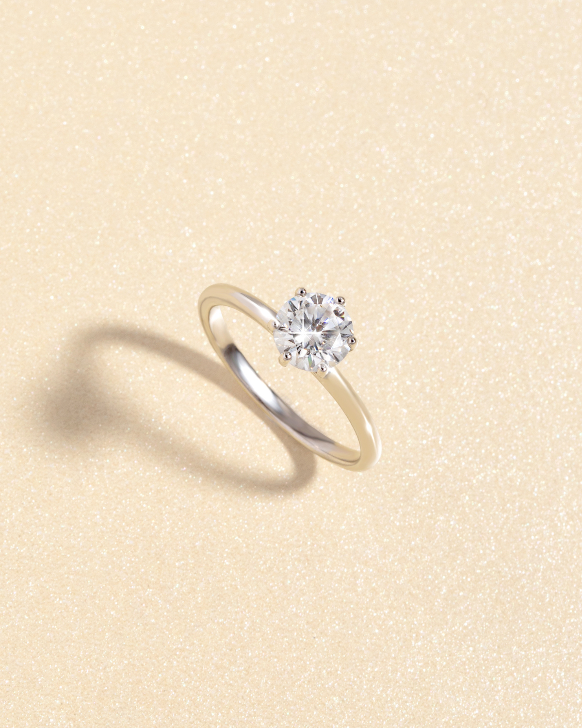 Angled view of the 1ct round solitaire moissanite engagement ring showing the stone setting and slim silver band.