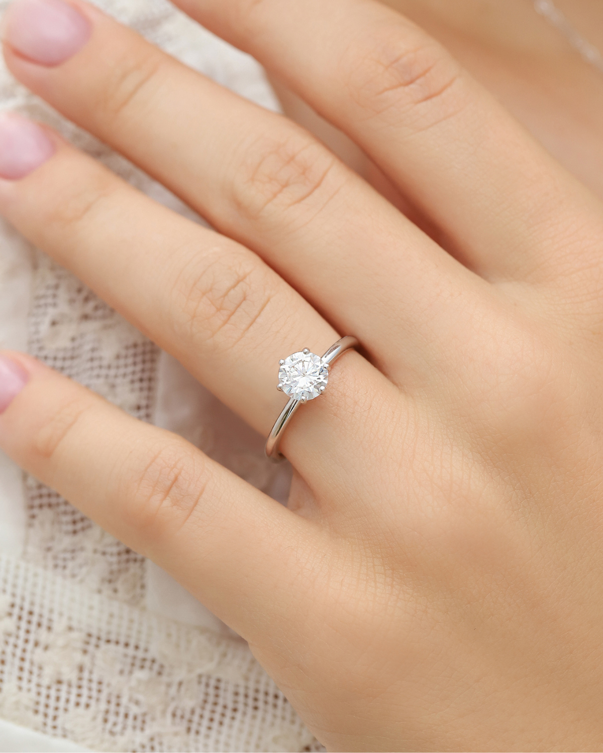 Close-up of the 1ct round solitaire moissanite engagement ring worn on the hand.