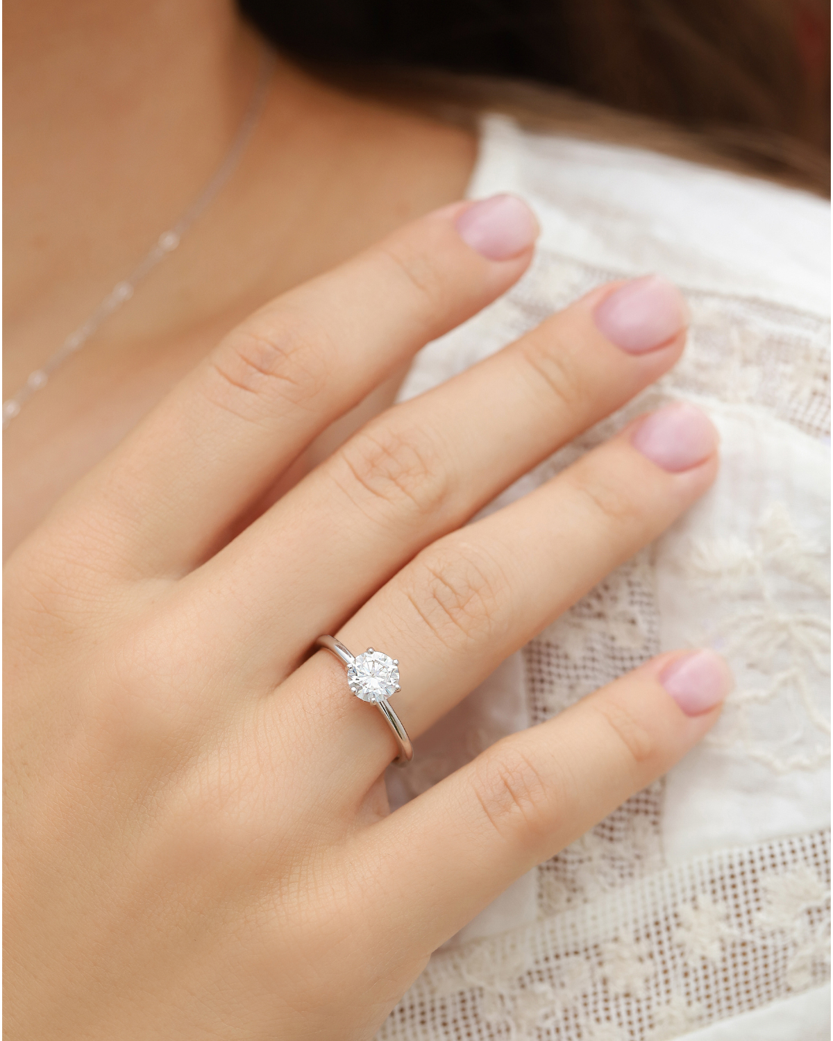 Close-up of the 1ct round solitaire moissanite engagement ring worn on the finger.