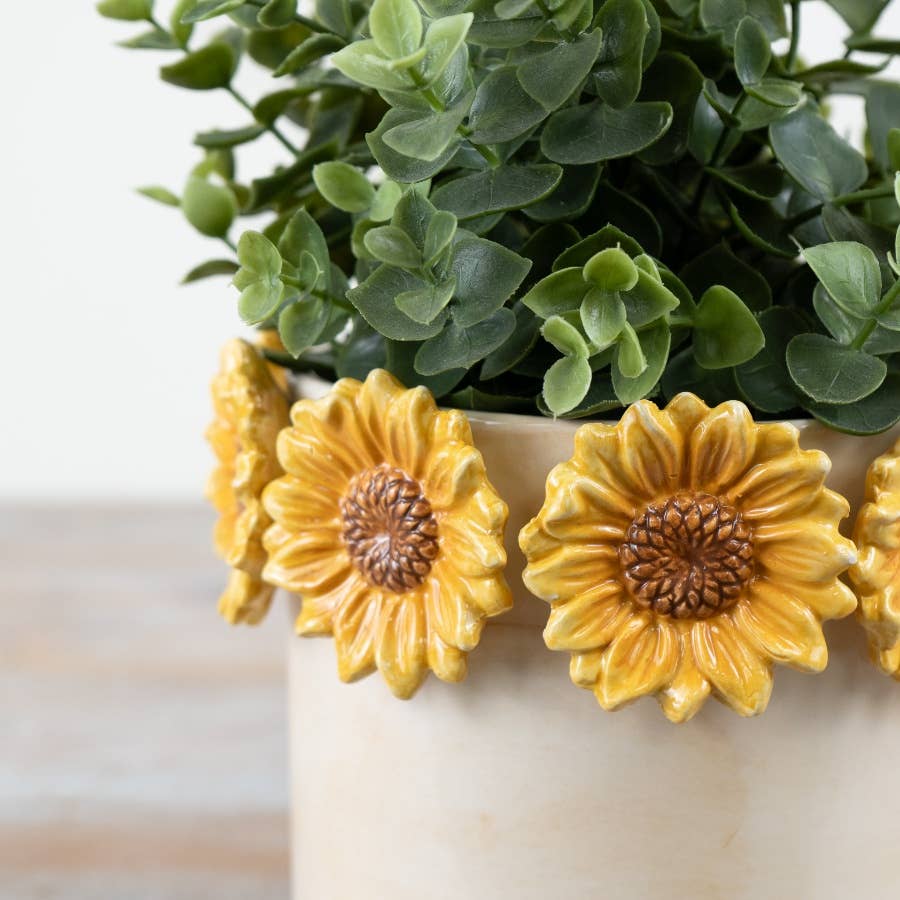Close-up of raised yellow sunflower detailing on cream plant pot