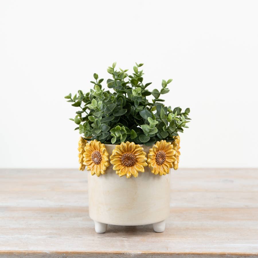 Cream and yellow sunflower plant pot styled with green foliage