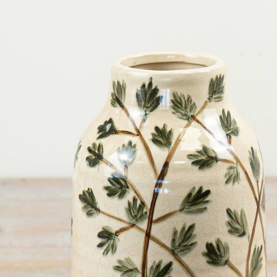 Close-up of the trailing green foliage and brown stem decoration on the cream ceramic vase