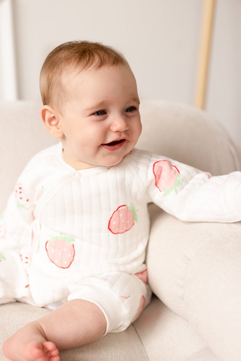 Baby wearing the soft Strawberry Bouclé Baby Grow Romper with strawberry print
