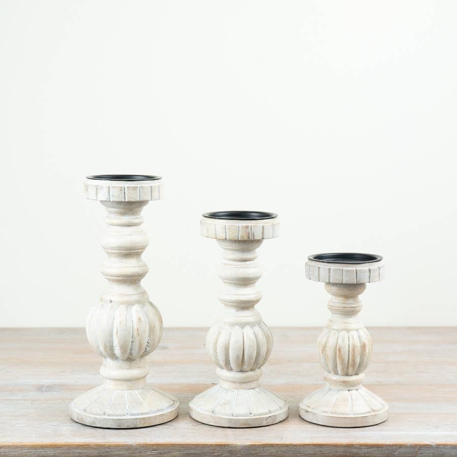 Group of coordinating white washed wooden candle stands with distressed finishes and traditional turned shapes