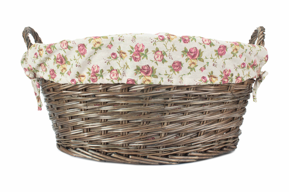 Antique Wash Willow Laundry Basket showing its traditional oval shape, floral fabric lining and integrated wicker handles