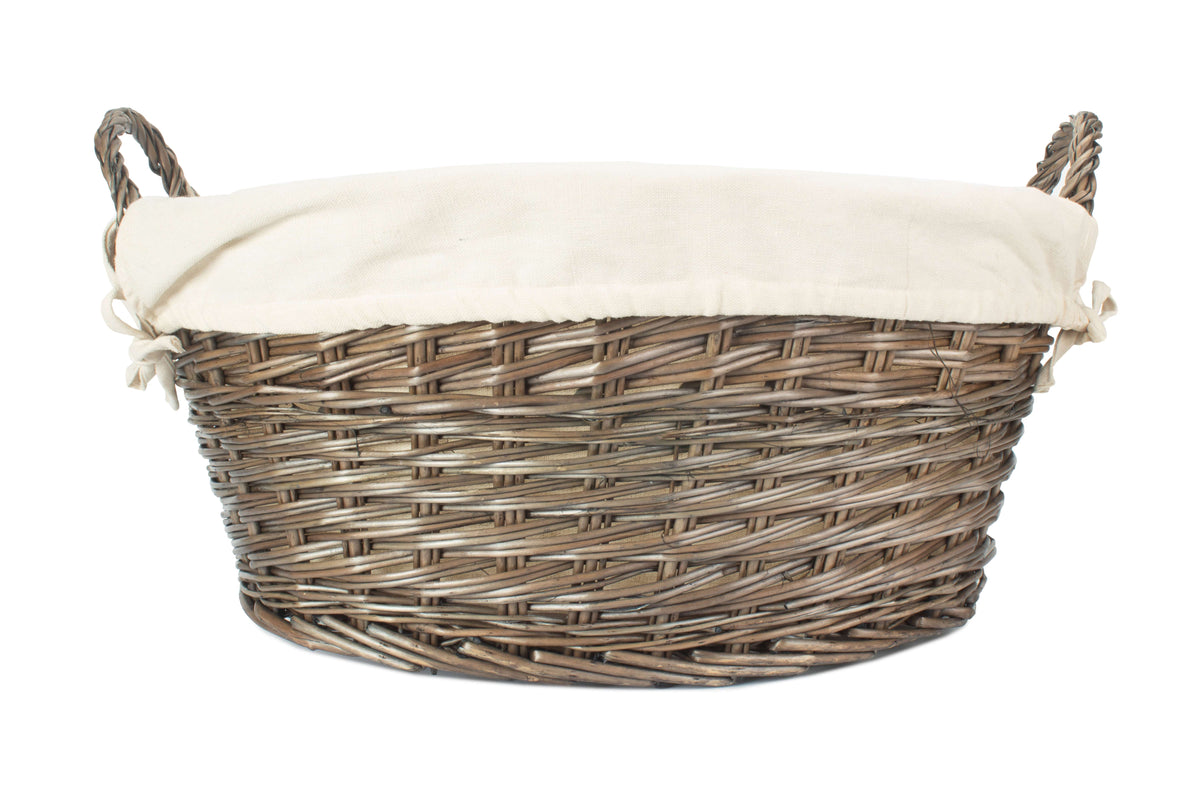 Antique wash willow laundry basket side view showing the oval wicker construction and white fabric lining