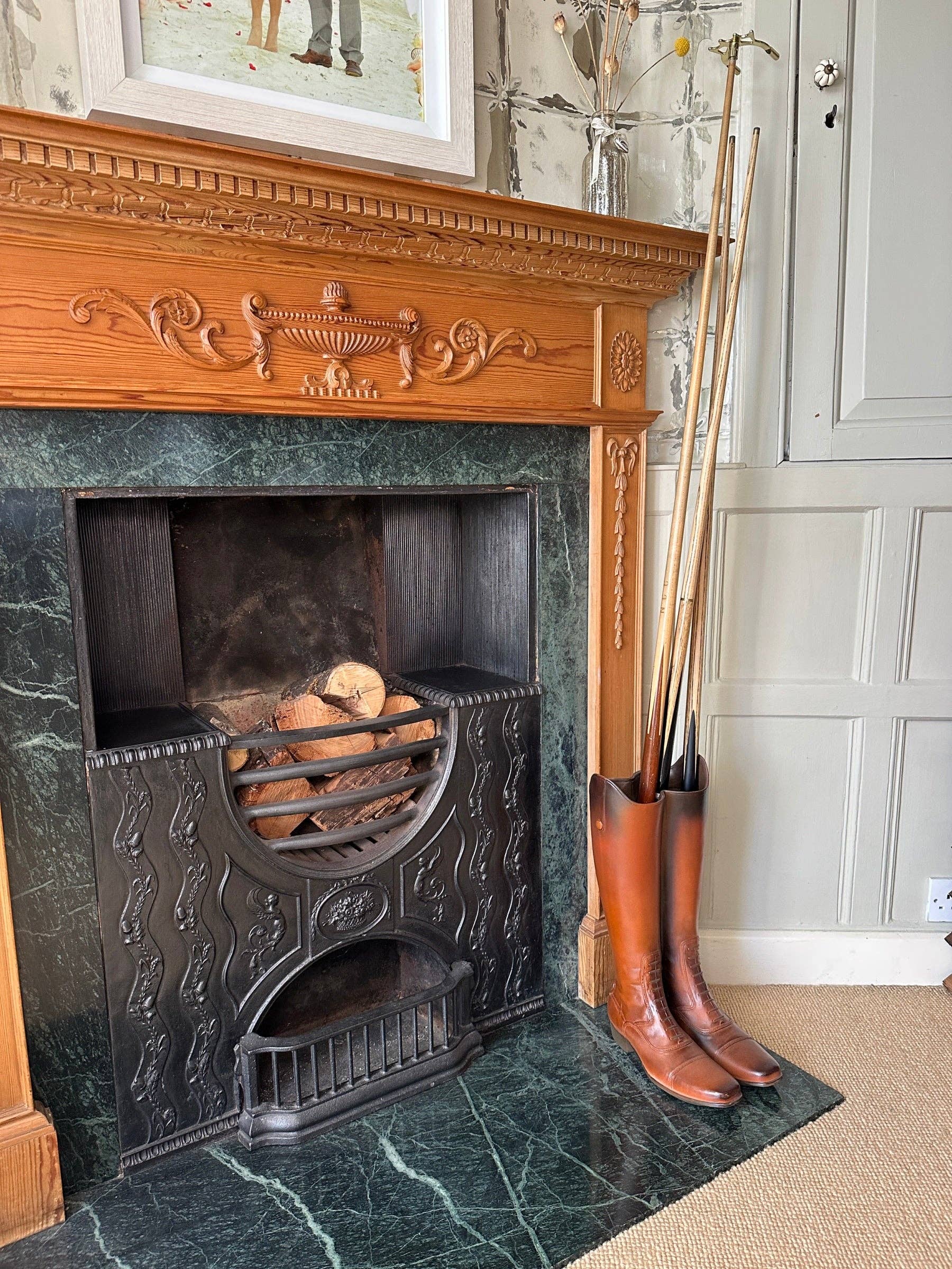 Brown boot umbrella stand styled beside a traditional fireplace