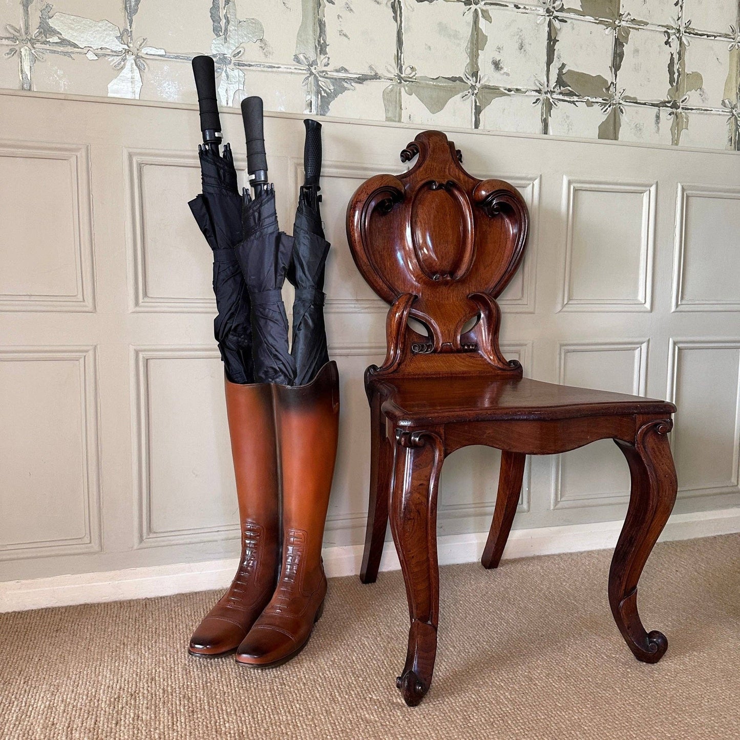 Boot umbrella stand displayed in a traditional hallway beside an occasional chair
