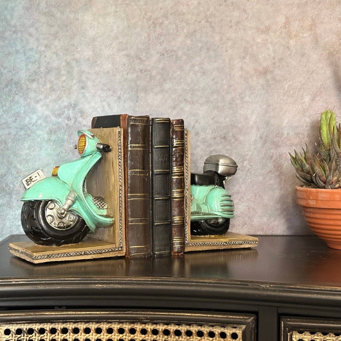 Vintage green scooter bookends styled with books on a traditional mantelpiece