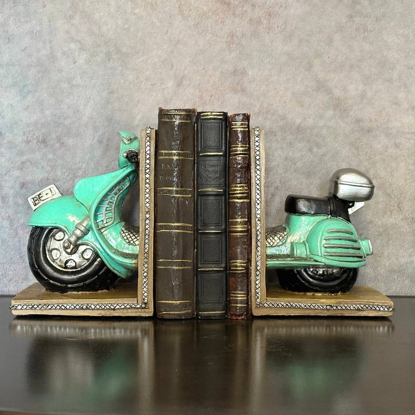Vintage scooter bookends displayed with books and decorative accessories on a green shelf