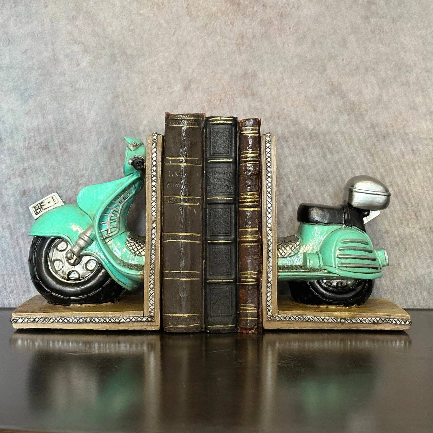 Vintage scooter bookends displayed with books and decorative accessories on a green shelf