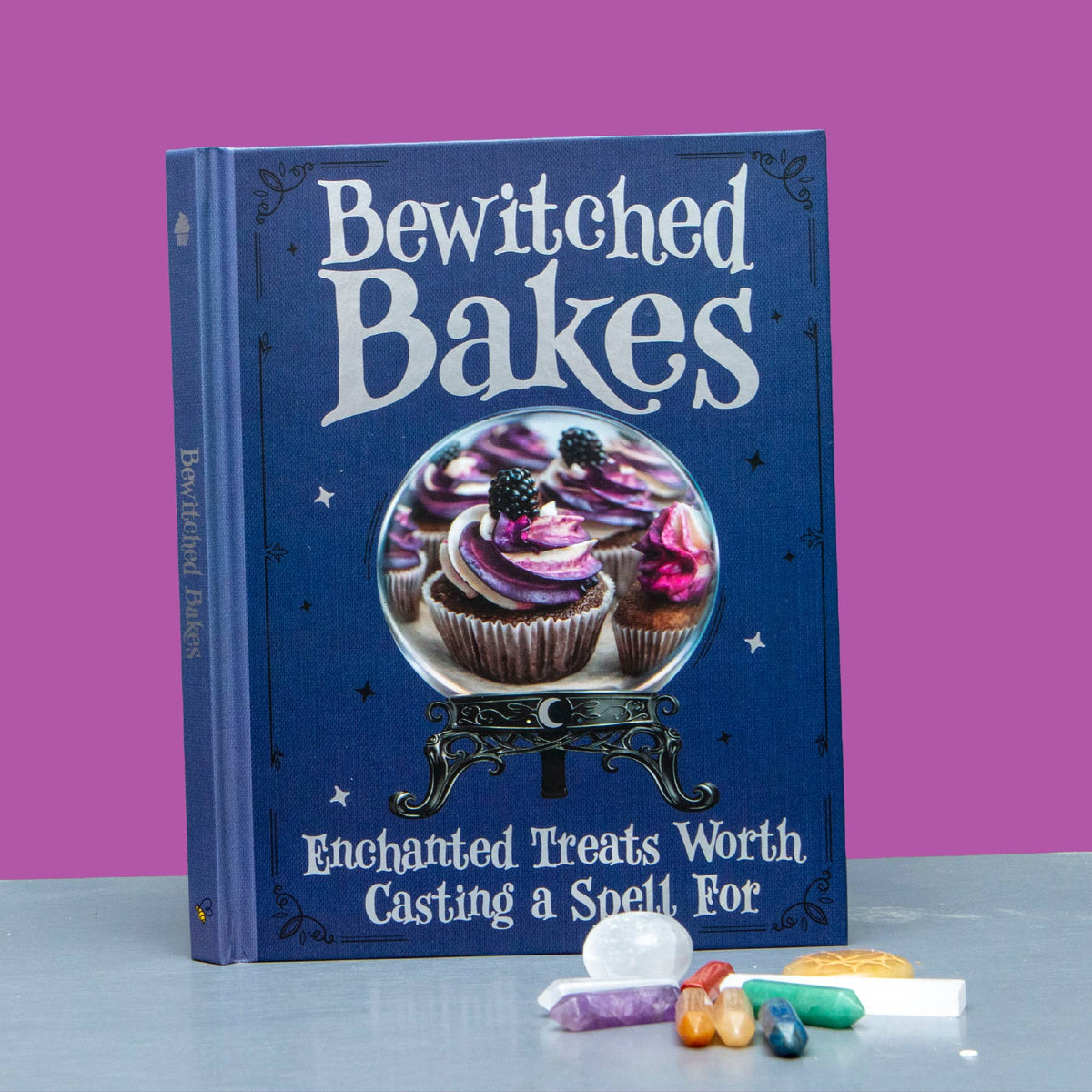 Bewitched Bakes witchy baking book with illustrated blue hardback cover featuring a decorated cupcake and gothic-inspired design.