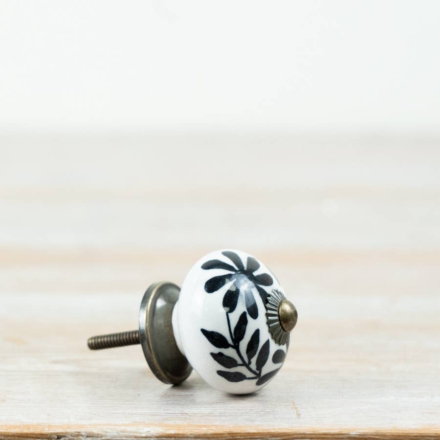 Black floral ceramic door knob with white background and metal fixing