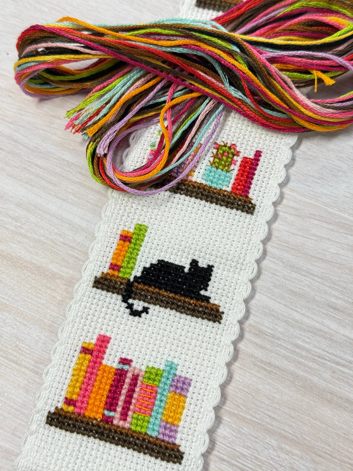 Book Lover Cross Stitch Bookmark Kit close-up showing the colourful bookshelf design with DMC embroidery threads
