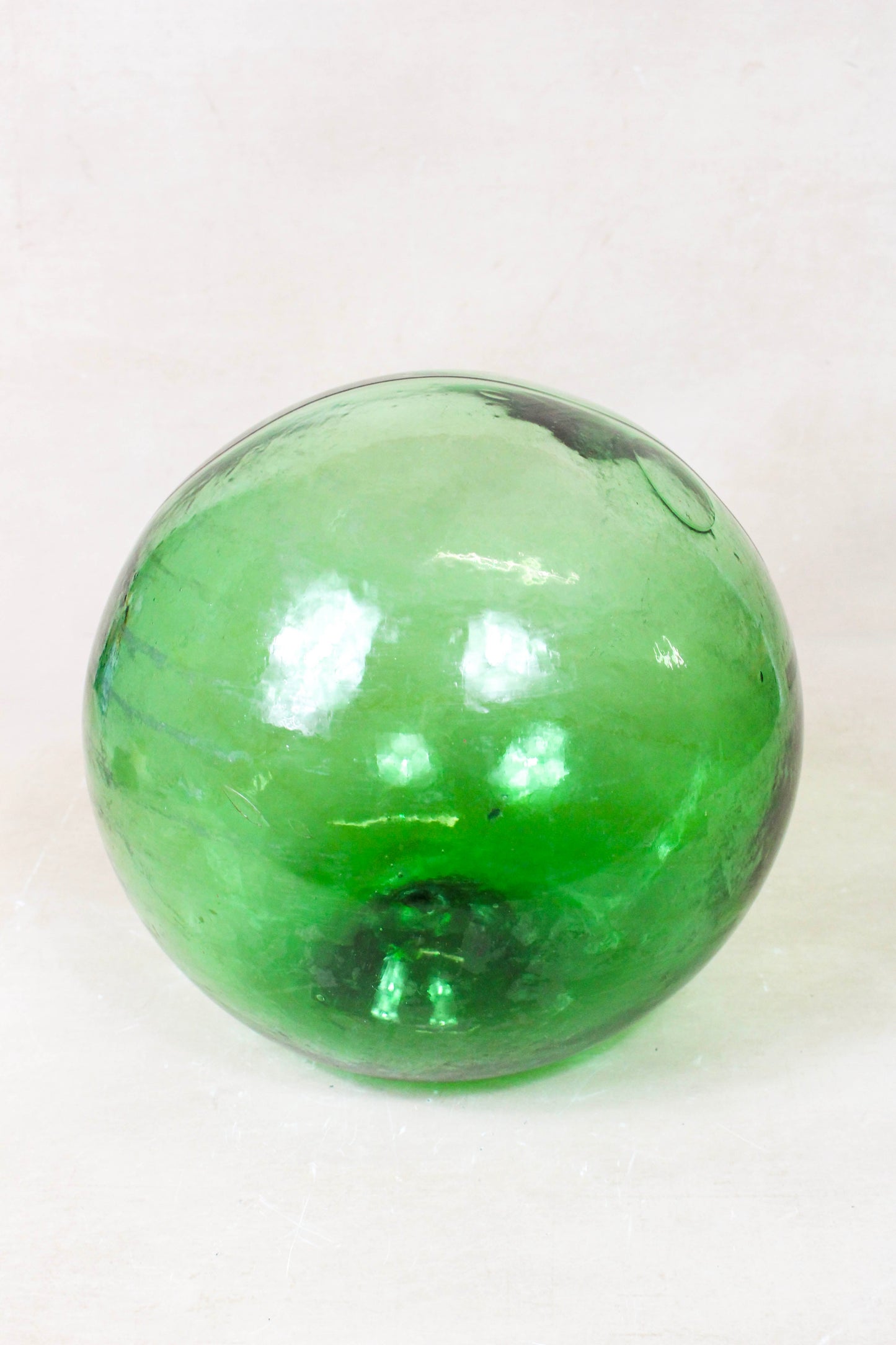 Antique hand-blown glass fishing buoy GB3 showing natural bubbles and variations in the green glass
