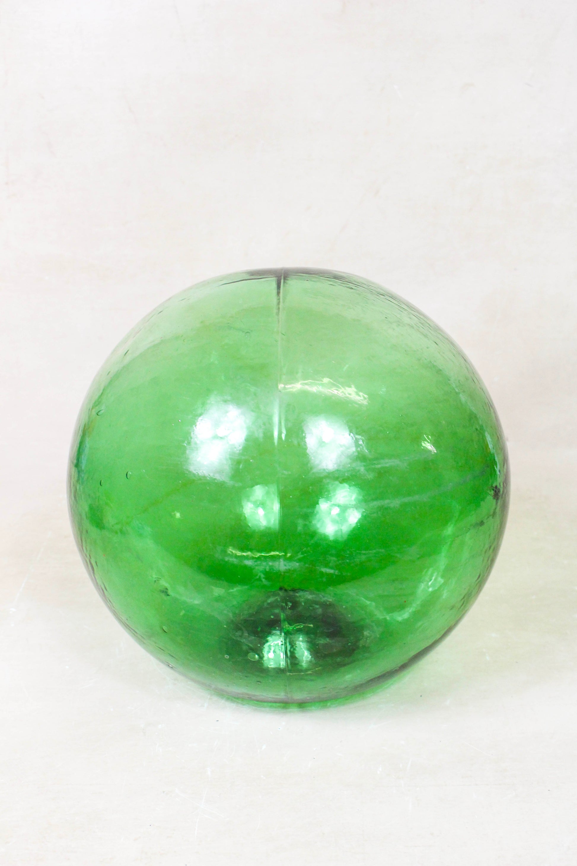 Antique green hand-blown glass fishing buoy GB3 showing its rounded form and luminous glass
