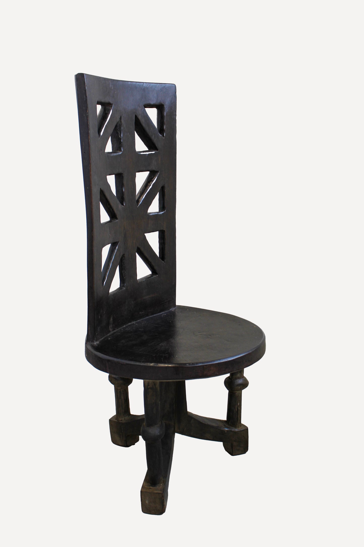 Hand-carved Makonde chair from Tanzania showing the round seat, carved backrest and sculptural legs
