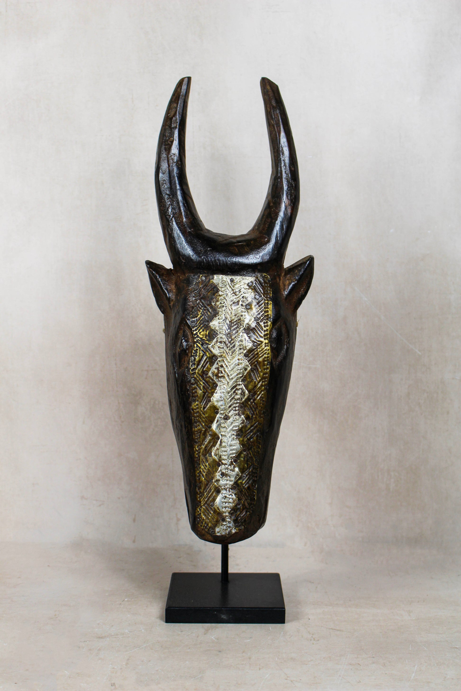 Mali bull mask 196.4 with upright horns, dark carved wood and hand-hammered repoussé metalwork
