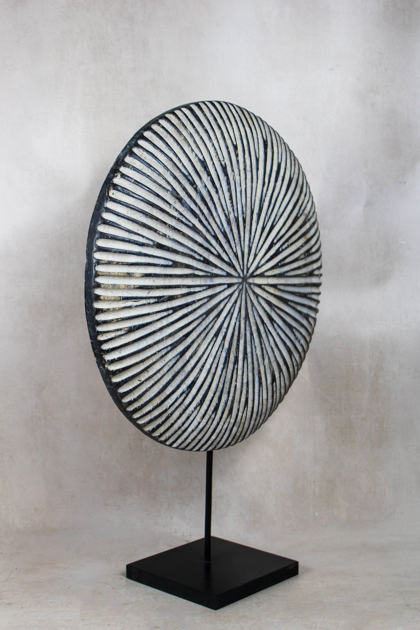 Round Cameroon shield 161.3 viewed at an angle showing the geometric pattern and black display stand
