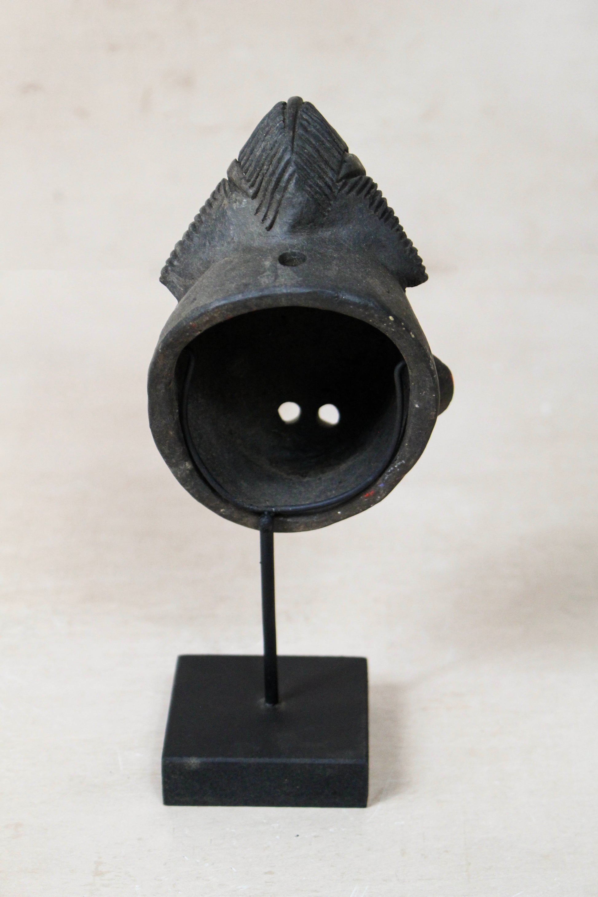 West African terracotta passport mask 189.2 viewed from the rear on its black display stand
