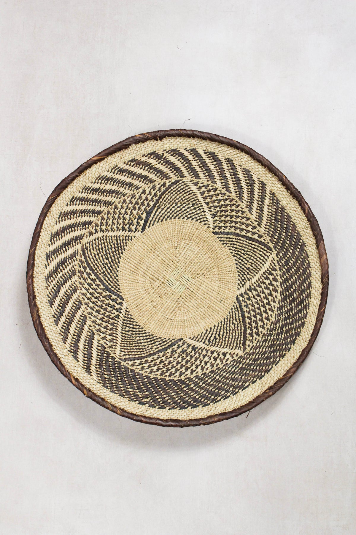 Handwoven Tonga wall basket from set No. 67 with dark geometric woven pattern
