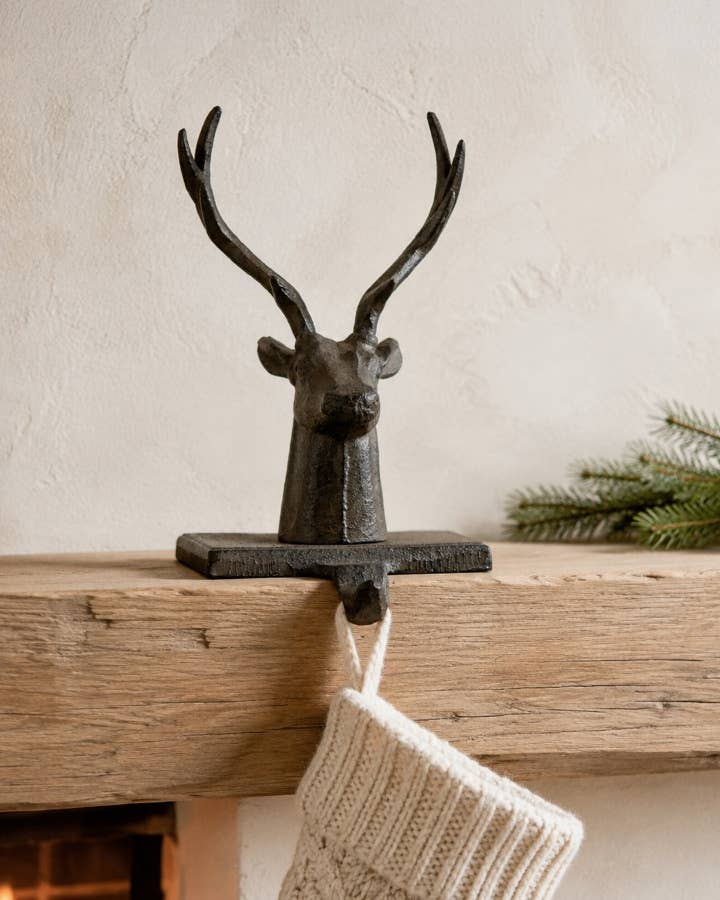 Cast Iron Stag Stocking Holder displayed on a mantelpiece with a Christmas stocking hanging from the hook