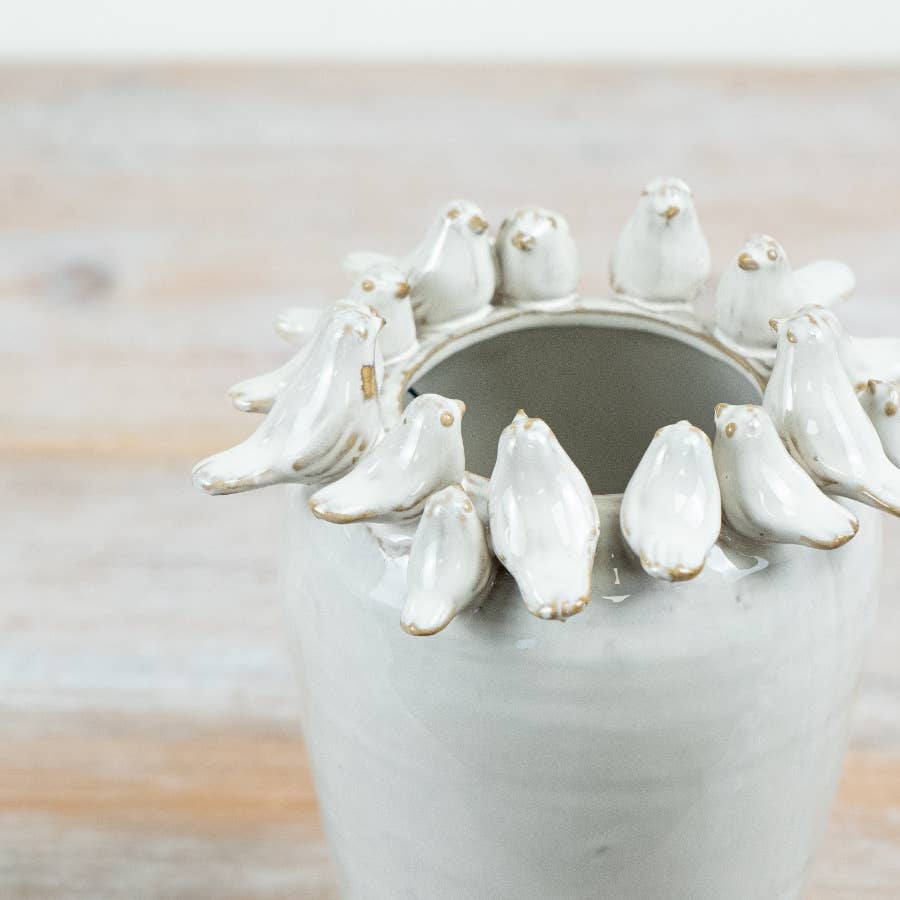 Close-up of sculpted birds around the rim of the white ceramic vase