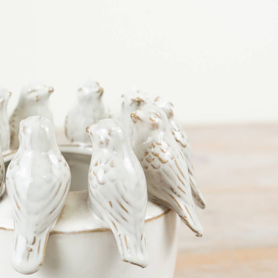 Close-up of sculpted birds around the rim of ceramic planter