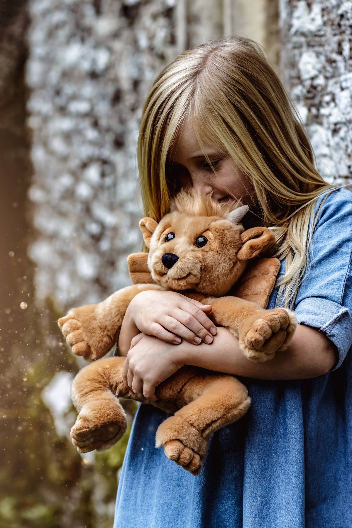 Charlie Bears Bartizan golden-brown gargoyle plush toy being cuddled by a child outdoors