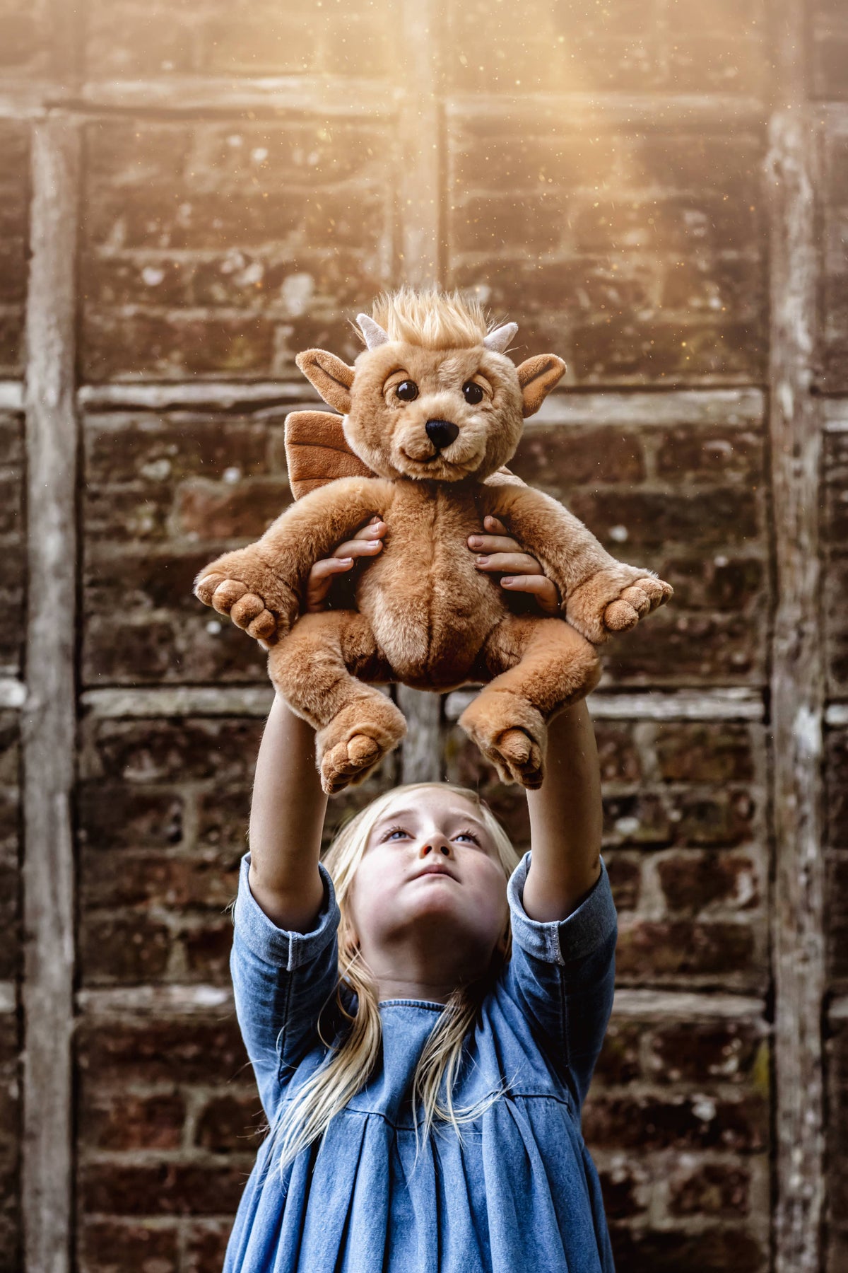 Charlie Bears Bartizan brown plush gargoyle being held outdoors in a rustic setting