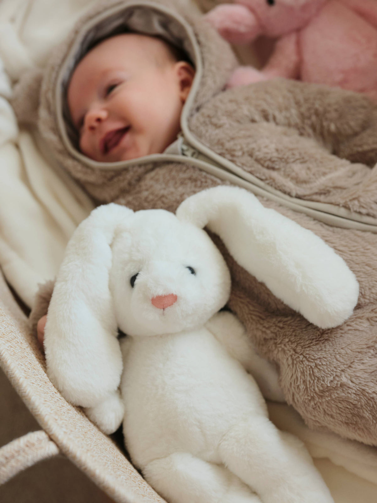 Charlie Bears Bramble Bunny white plush rabbit beside a baby