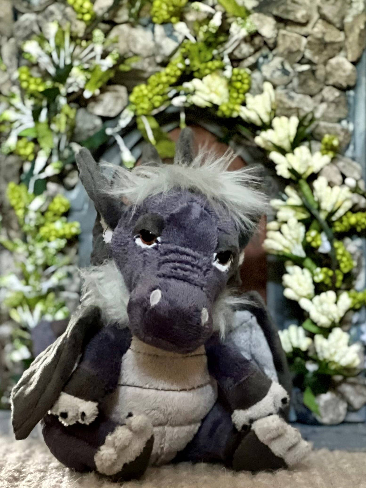 Charlie Bears Cuddle Cub Soot grey plush dragon in a garden setting