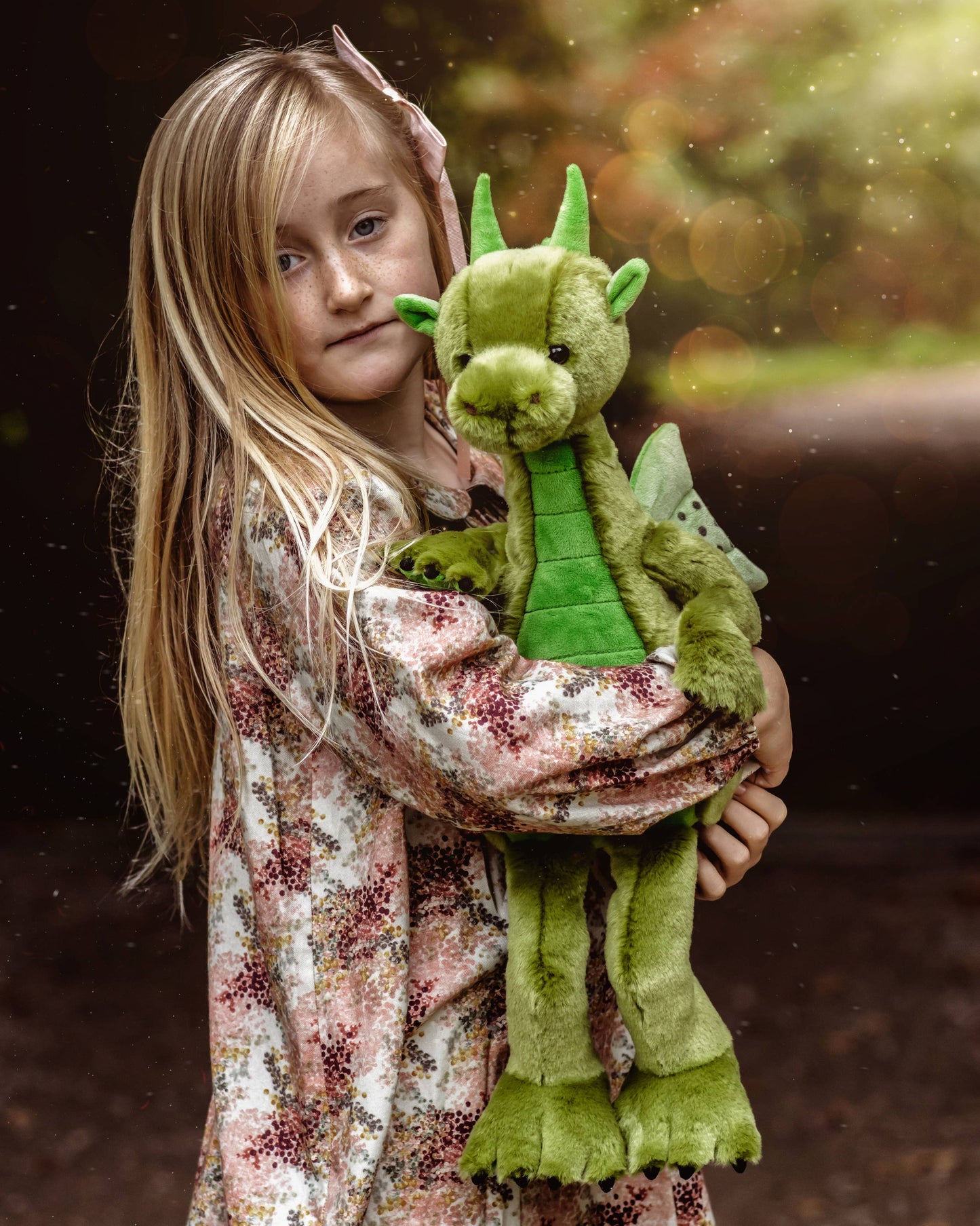 Charlie Bears Deck dragon plush being cuddled in an outdoor lifestyle setting