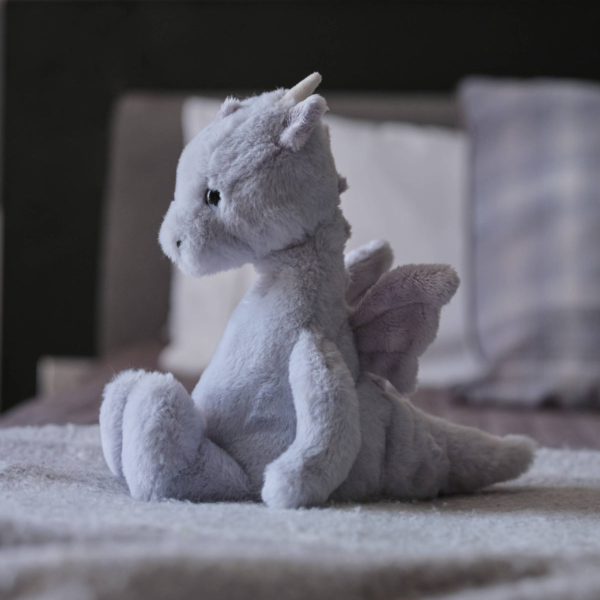 Charlie Bears Draco Dragon cloudy grey plush soft toy in a cosy bedroom setting