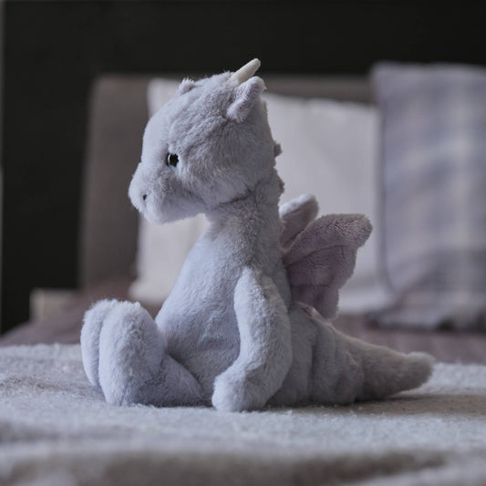 Charlie Bears Draco Dragon cloudy grey plush soft toy in a cosy bedroom setting