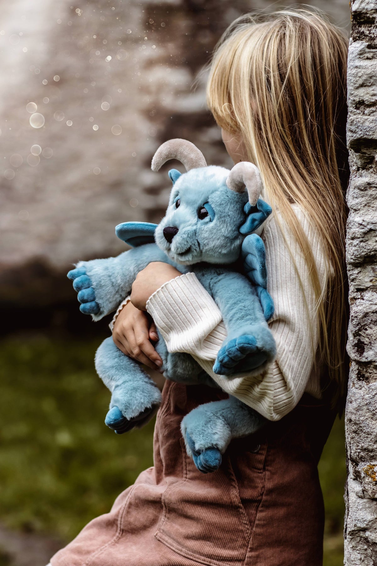 Charlie Bears Drawbridge sky-blue plush gargoyle being carried outdoors by a child