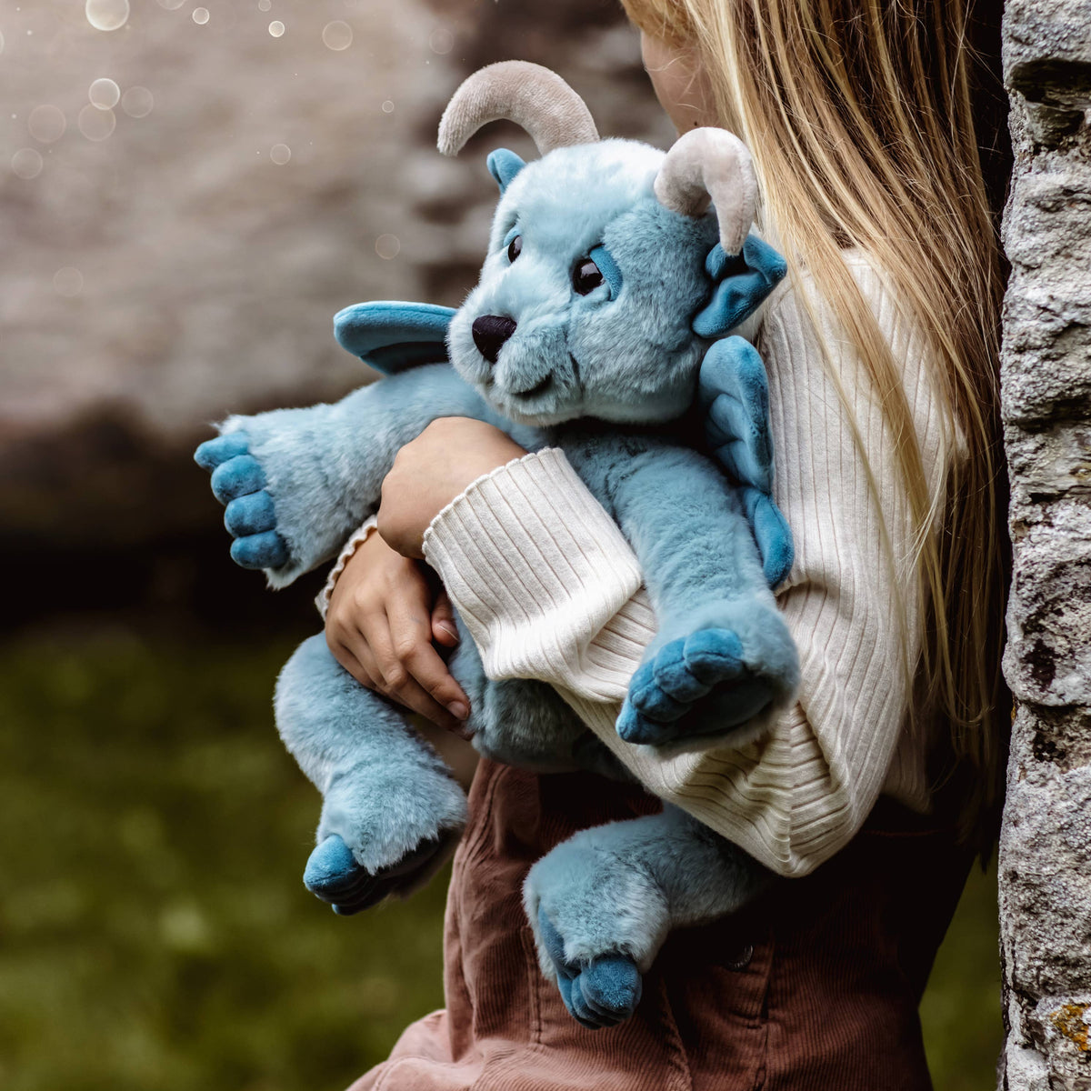 Charlie Bears Drawbridge sky-blue plush gargoyle being carried outdoors by a child