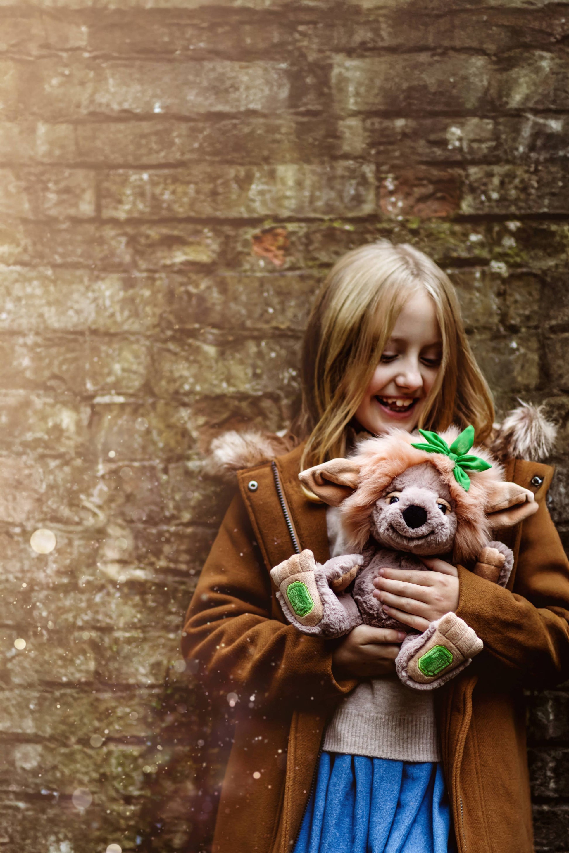 Charlie Bears Emerald Lou plush troll being held by a child in a woodland setting