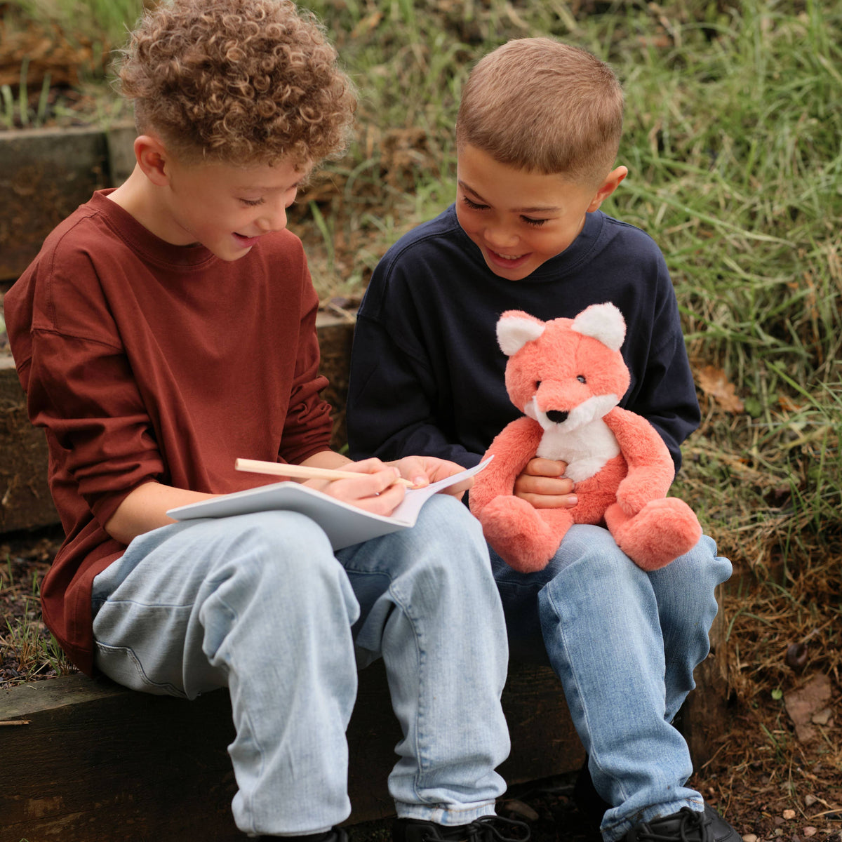 Charlie Bears Folly Fox orange plush fox being held outdoors by children