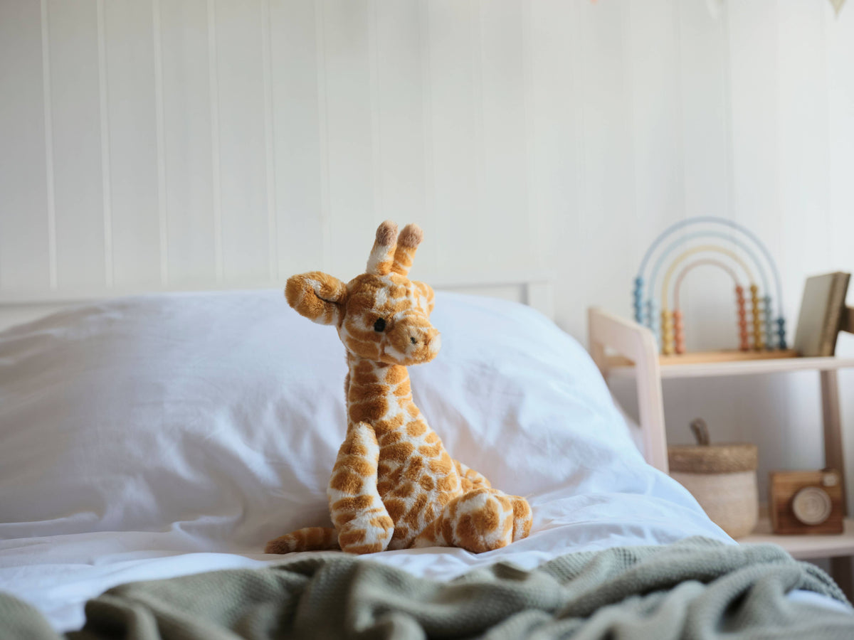 Charlie Bears Gilbert Giraffe plush soft toy displayed in a softly styled nursery