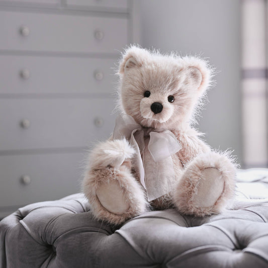 Charlie Bears Jelly Bean light grey plush teddy bear with organza bow displayed on an upholstered seat