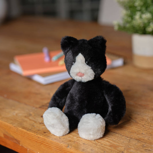 Charlie Bears Pudgy Kitten black and white plush cat displayed on a wooden table