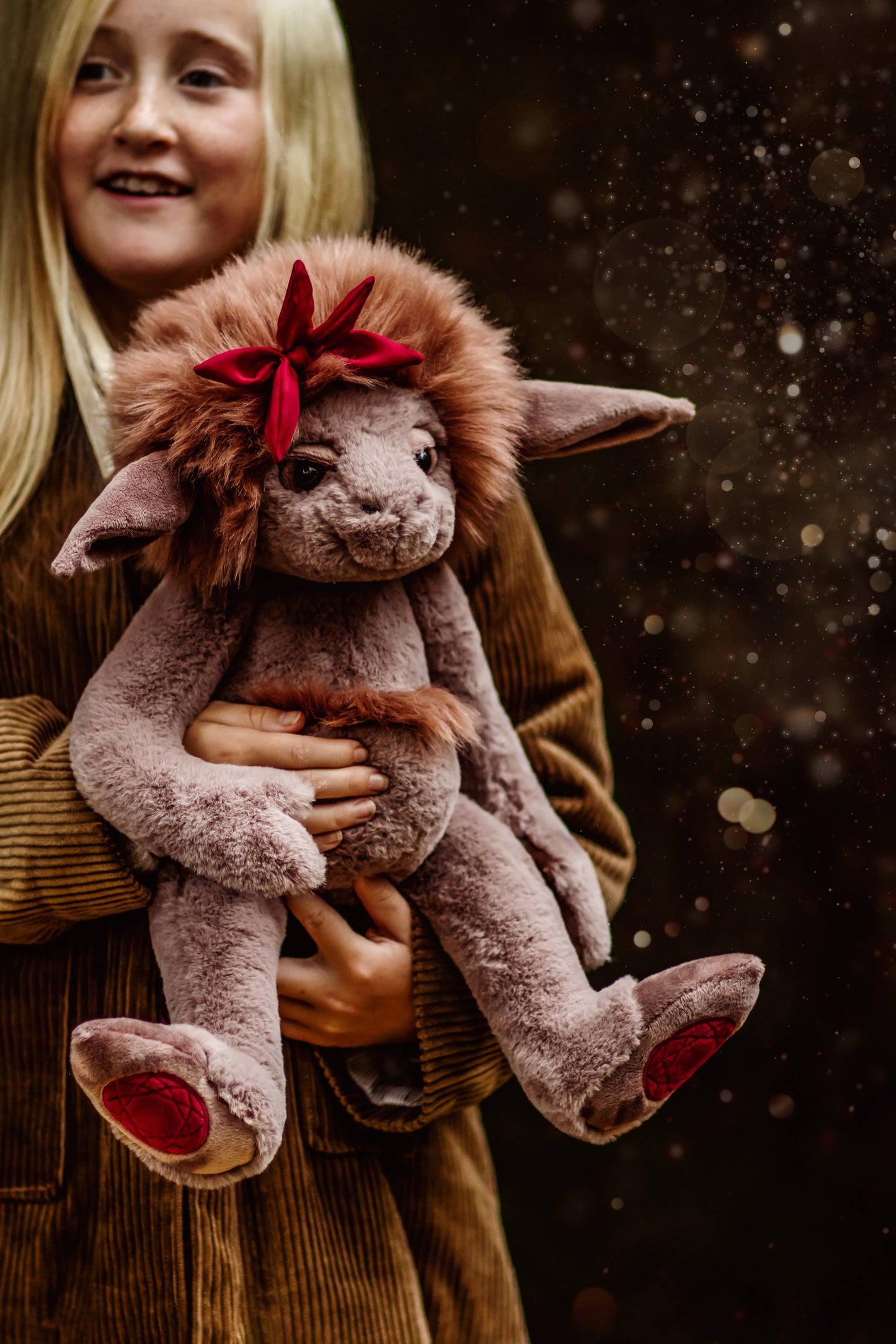 Charlie Bears Ruby Roo plush character being cuddled in a cosy lifestyle setting