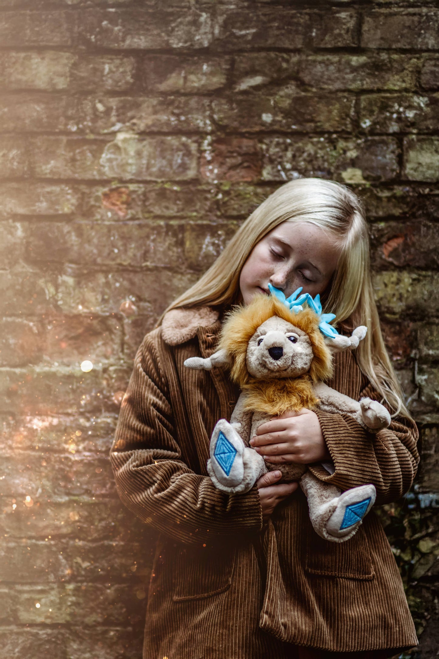 Charlie Bears Topaz Blu plush character being cuddled in a cosy lifestyle setting