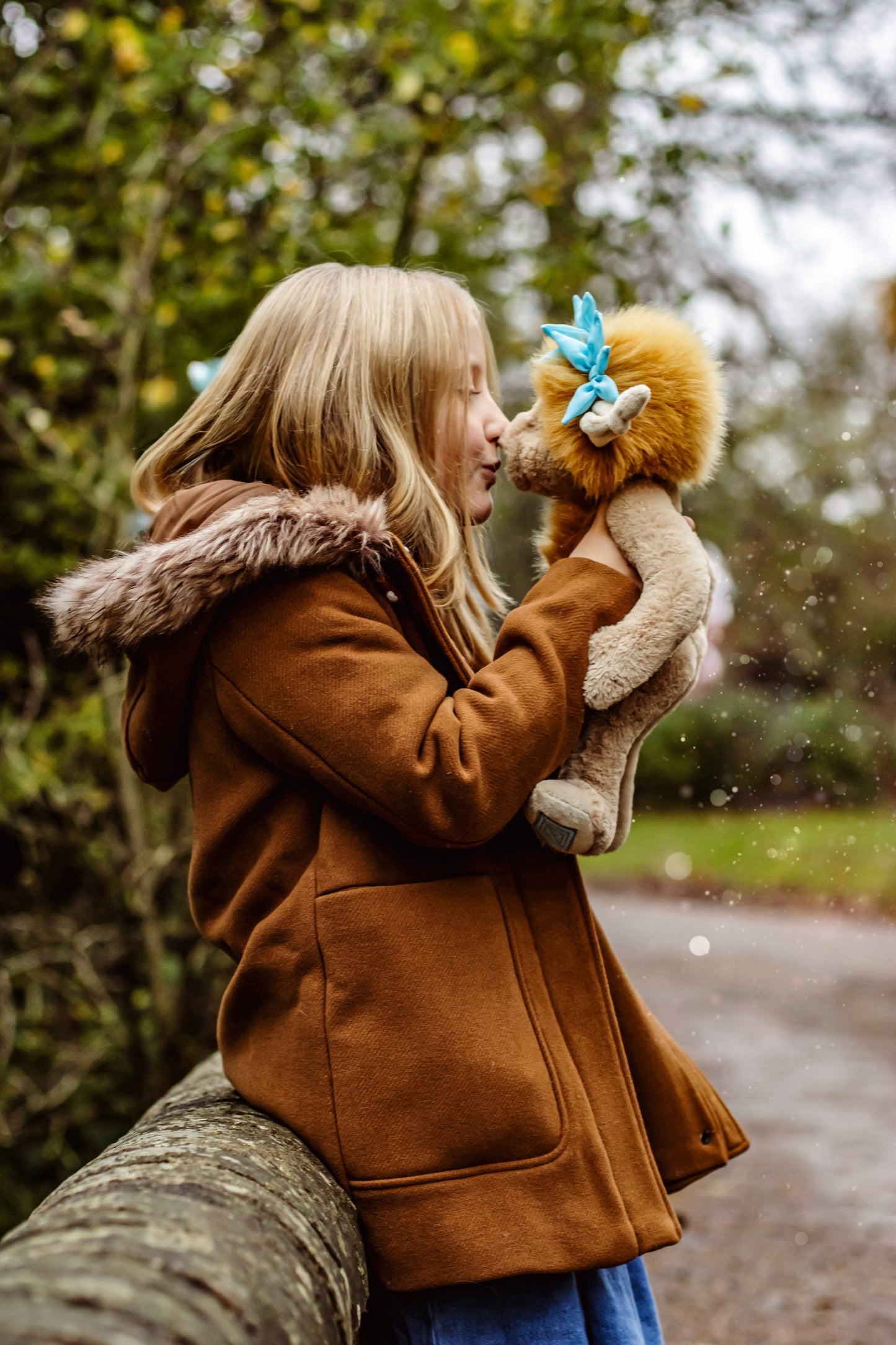 Charlie Bears Topaz Blu plush character being cuddled in a cosy lifestyle setting