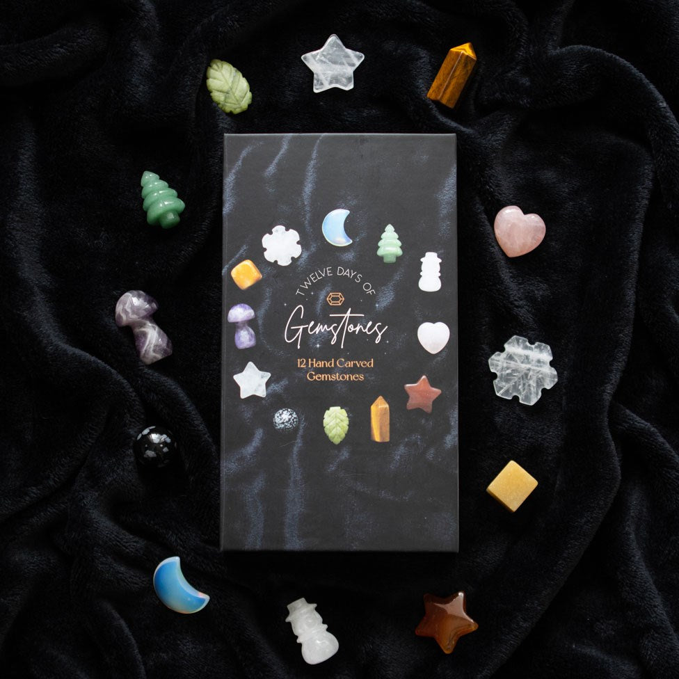 12-Day Christmas Crystal Advent Calendar displayed on black fabric with twelve colourful carved festive gemstones