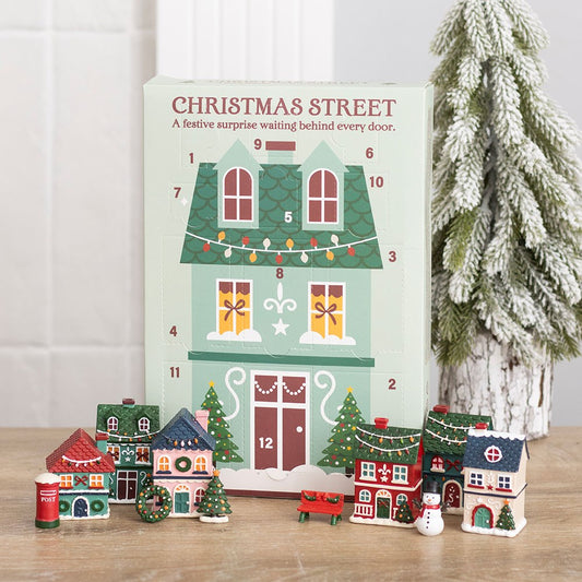12-Day Christmas Street Scene Advent Calendar displayed with miniature festive village houses and a snowy Christmas tree