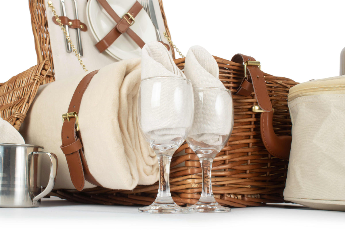 Two wine glasses with cream napkins and picnic accessories from the Deluxe 2 Person Willow Picnic Hamper
