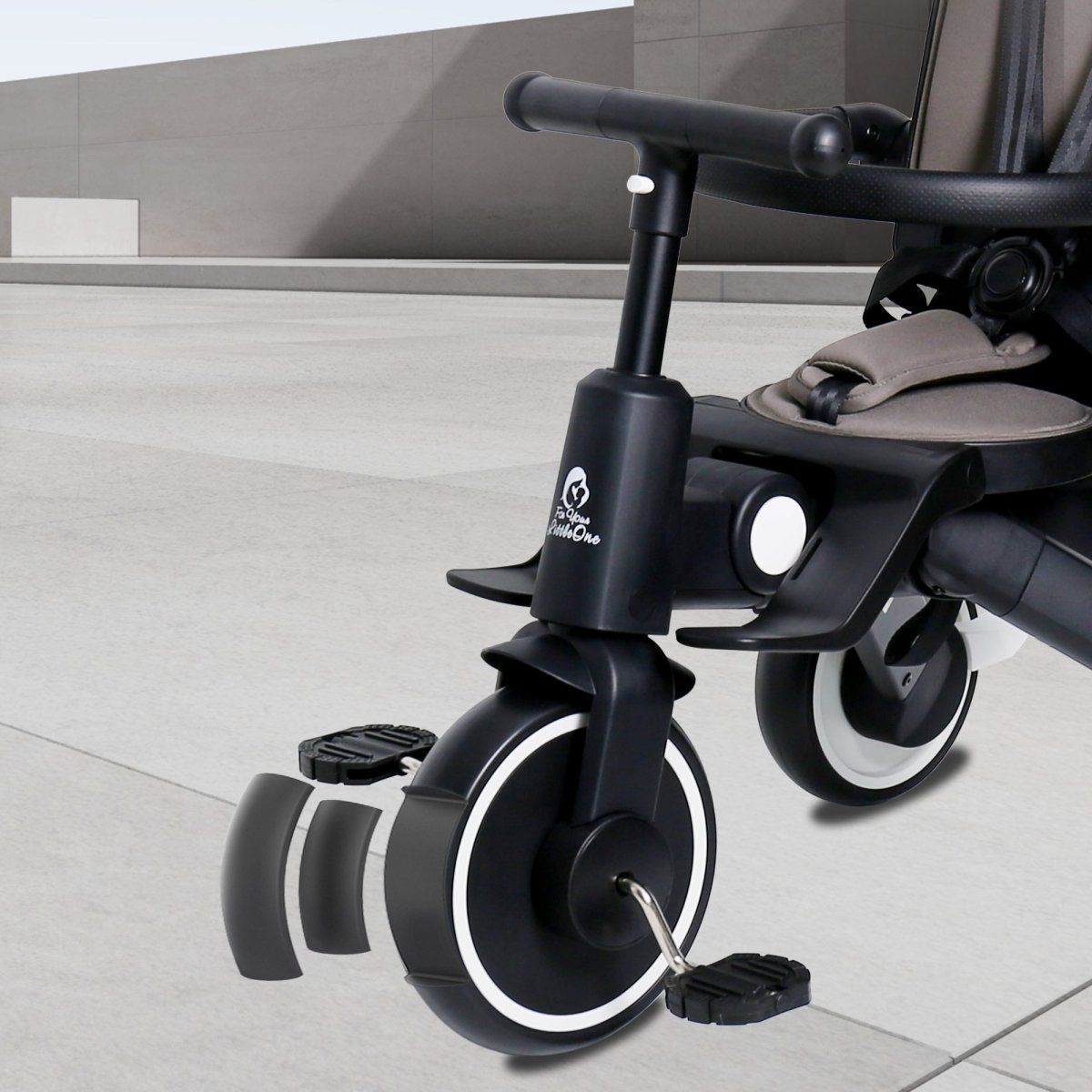 Black and gray child's tricycle on a light gray floor.